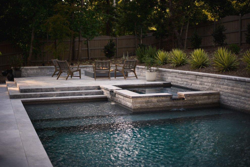 Esempio di una piscina monocorsia design rettangolare di medie dimensioni e dietro casa con una vasca idromassaggio e pavimentazioni in pietra naturale