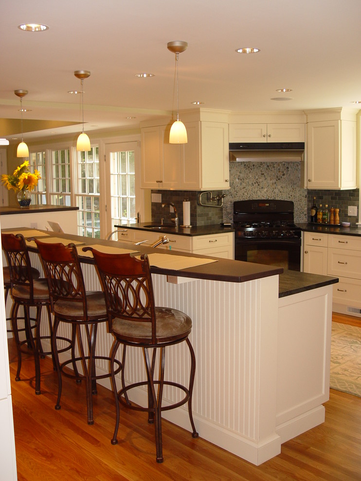 Inspiration for a transitional kitchen remodel in Boston with an undermount sink, recessed-panel cabinets, white cabinets, granite countertops, black appliances and an island