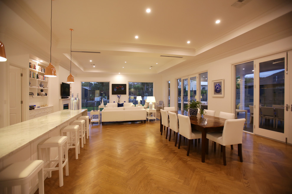 This is an example of a large beach style kitchen/dining combo in Adelaide with white walls, medium hardwood floors, a standard fireplace and a wood fireplace surround.