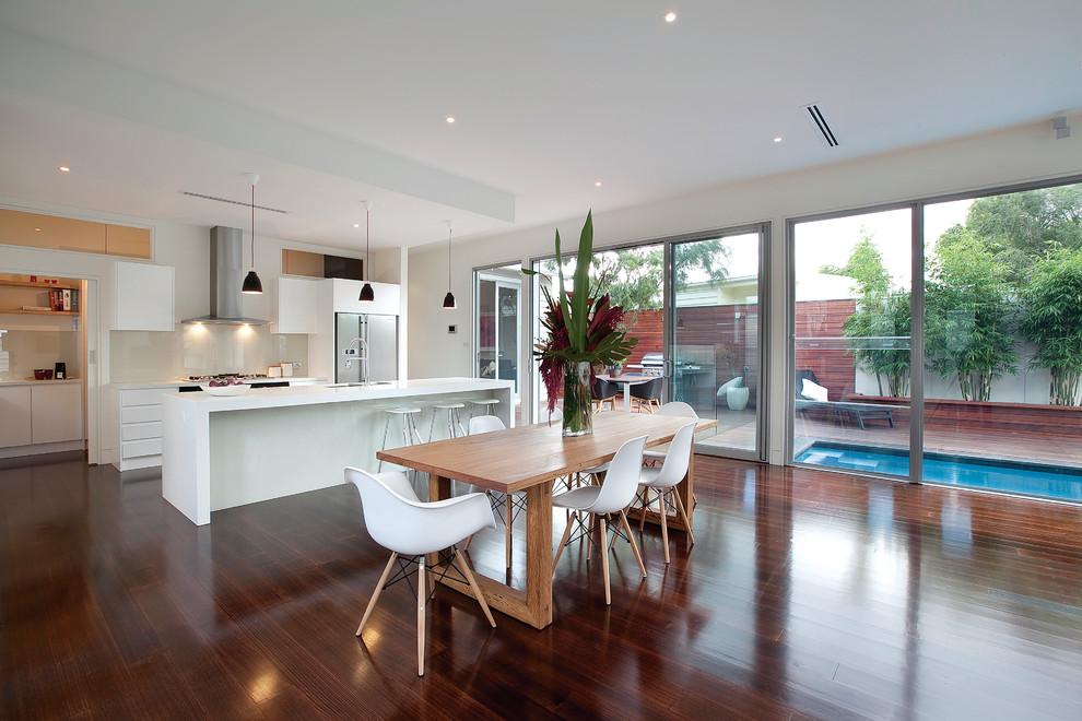 This is an example of a contemporary open plan dining in Melbourne with white walls and dark hardwood floors.