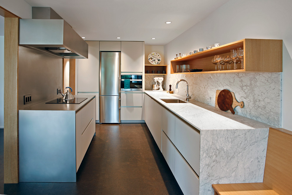 Photo of a mid-sized midcentury l-shaped eat-in kitchen in Seattle with an undermount sink, flat-panel cabinets, white cabinets, solid surface benchtops, stainless steel appliances and cork floors.