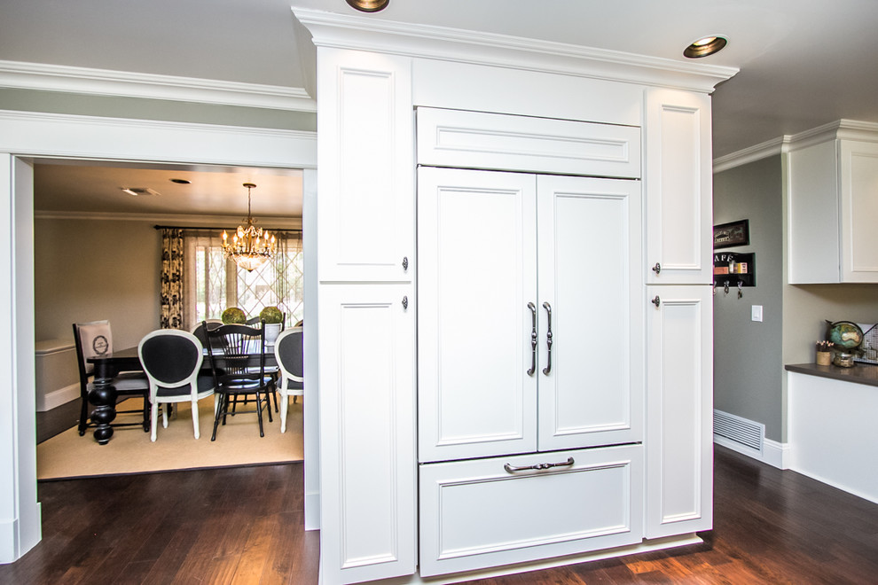 Example of a large transitional u-shaped dark wood floor and brown floor eat-in kitchen design in Phoenix with a double-bowl sink, recessed-panel cabinets, white cabinets, quartzite countertops, white backsplash, ceramic backsplash, paneled appliances and an island