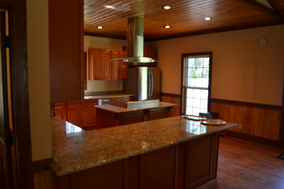Kitchen - mid-sized rustic u-shaped medium tone wood floor kitchen idea in Atlanta with raised-panel cabinets, brown cabinets, granite countertops, stainless steel appliances and an island