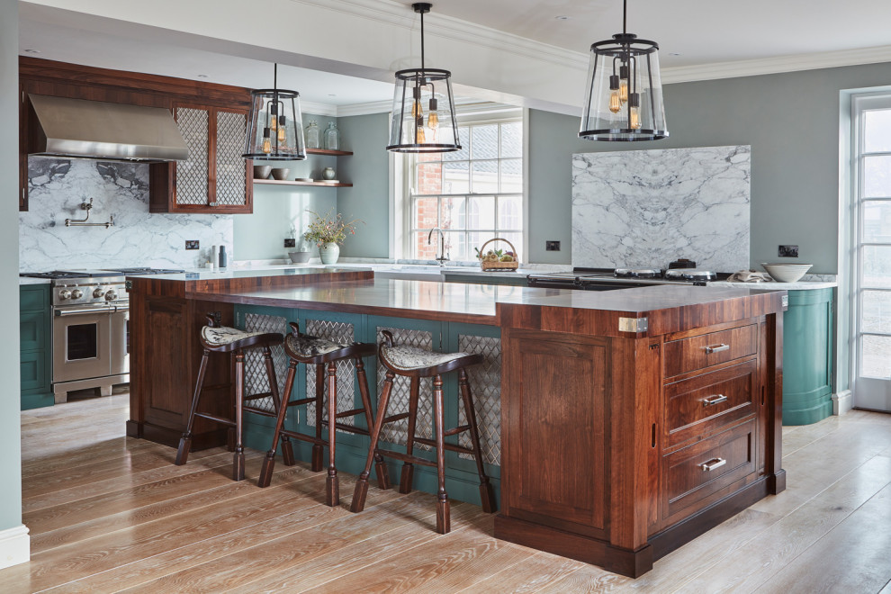 Large traditional u-shaped eat-in kitchen in Other with a farmhouse sink, marble benchtops, marble splashback, stainless steel appliances, with island, white benchtop, recessed-panel cabinets, green cabinets, white splashback, medium hardwood floors and brown floor.