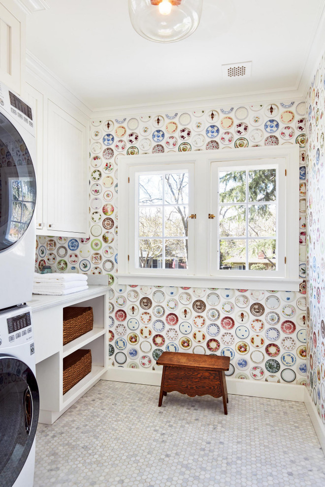 Design ideas for a mid-sized traditional single-wall dedicated laundry room in San Francisco with shaker cabinets, white cabinets, multi-coloured walls, marble floors, a stacked washer and dryer, white floor, white benchtop and wallpaper.