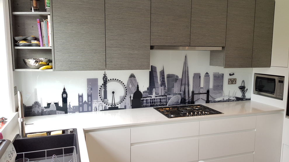 Photo of a mid-sized modern u-shaped open plan kitchen in London with an integrated sink, flat-panel cabinets, white cabinets, quartzite benchtops, multi-coloured splashback, glass sheet splashback, stainless steel appliances, ceramic floors, a peninsula, white floor and white benchtop.