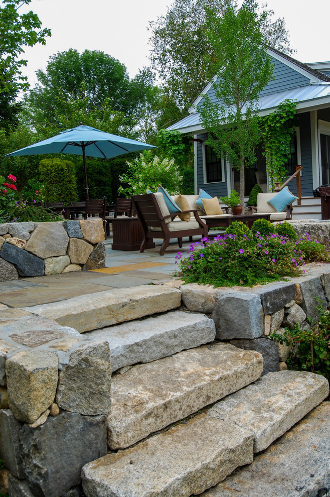Mid-sized country backyard patio in Boston with natural stone pavers and no cover.