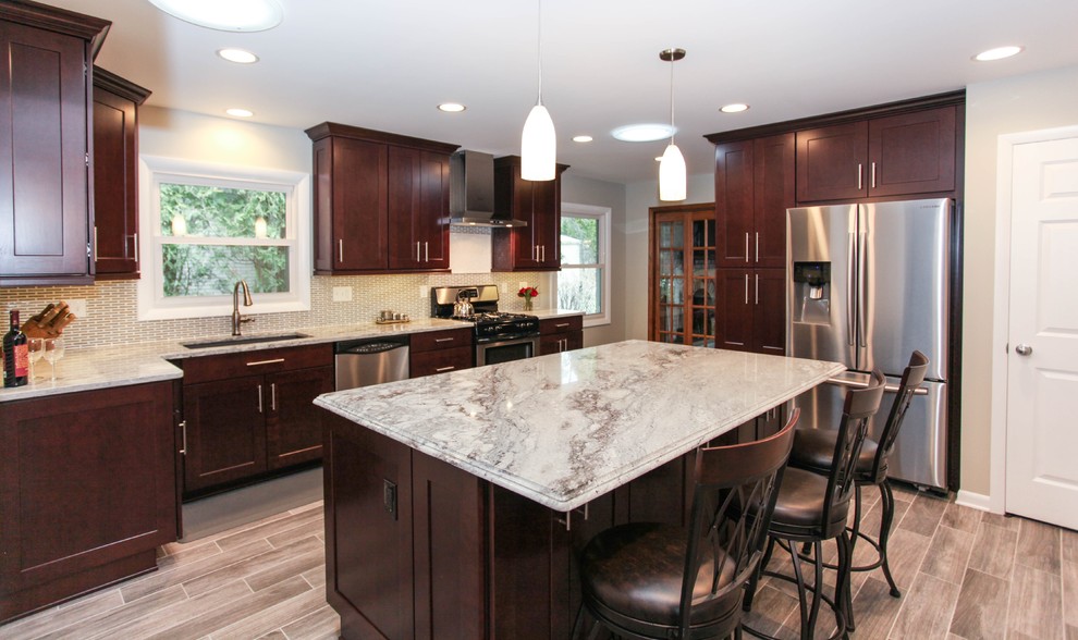 Example of a large transitional u-shaped porcelain tile eat-in kitchen design in Chicago with an undermount sink, recessed-panel cabinets, dark wood cabinets, granite countertops, gray backsplash, glass tile backsplash, stainless steel appliances and an island