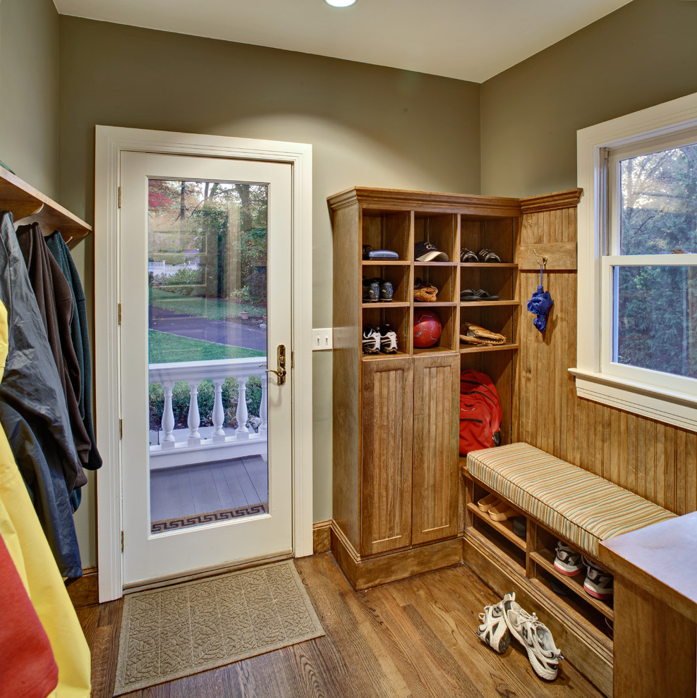 This is an example of a traditional mudroom in New York with beige walls, medium hardwood floors, a single front door and a glass front door.