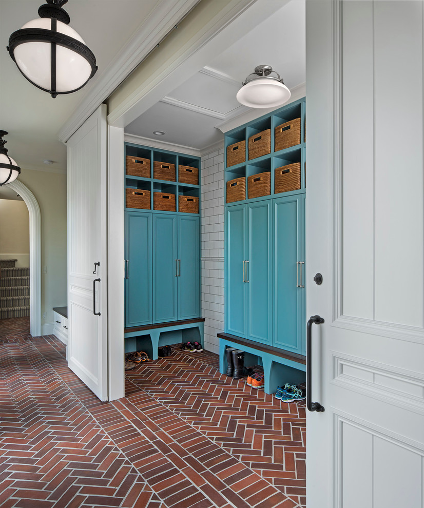 Inspiration for a large traditional mudroom in Detroit with brick floors, beige walls and red floor.