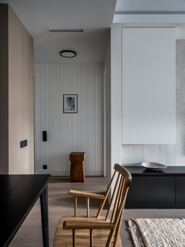 Idee per una sala da pranzo aperta verso il soggiorno design di medie dimensioni con pareti bianche, pavimento in legno massello medio, pavimento grigio, soffitto ribassato e pannellatura