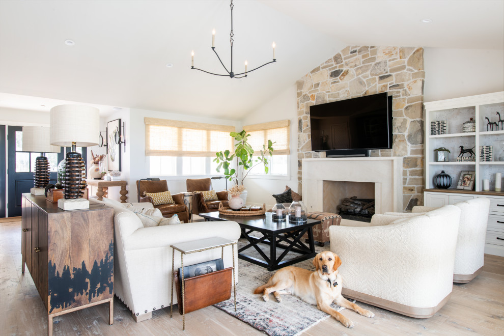 Design ideas for a country open concept family room in Los Angeles with white walls, light hardwood floors, a standard fireplace, a wall-mounted tv and vaulted.