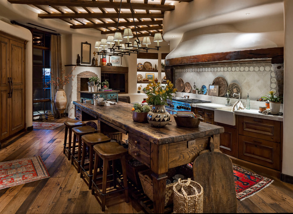 This is an example of a large galley eat-in kitchen in Phoenix with a farmhouse sink, recessed-panel cabinets, medium wood cabinets, limestone benchtops, white splashback, mosaic tile splashback, stainless steel appliances, medium hardwood floors, with island and brown floor.