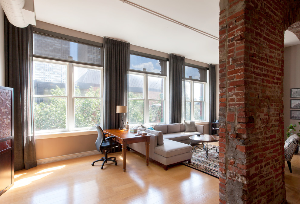This is an example of a mid-sized industrial loft-style bedroom in Philadelphia with beige walls, light hardwood floors, no fireplace and beige floor.