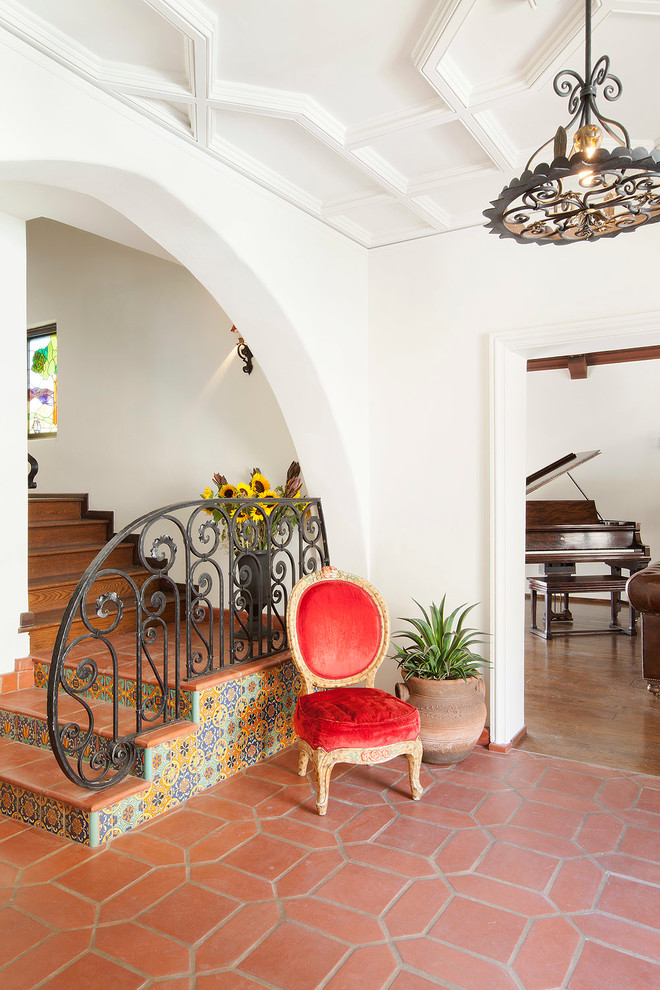 This is an example of a mediterranean terracotta l-shaped staircase in Los Angeles with tile risers and metal railing.