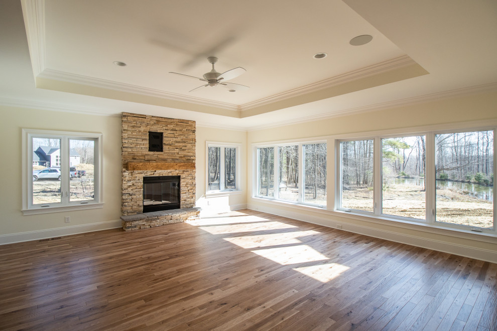 Inspiration for an expansive classic open plan games room in Cleveland with beige walls, medium hardwood flooring, a standard fireplace, a stacked stone fireplace surround, brown floors and a drop ceiling.