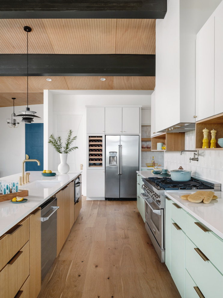 Inspiration for an expansive midcentury kitchen/diner in Austin with a built-in sink, flat-panel cabinets, turquoise cabinets, engineered stone countertops, white splashback, porcelain splashback, stainless steel appliances, medium hardwood flooring, an island, beige floors, white worktops and a wood ceiling.
