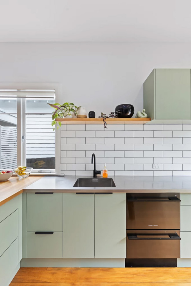 オークランドにあるお手頃価格の中くらいなコンテンポラリースタイルのおしゃれなキッチン (一体型シンク、フラットパネル扉のキャビネット、緑のキャビネット、白いキッチンパネル、セメントタイルのキッチンパネル、シルバーの調理設備) の写真