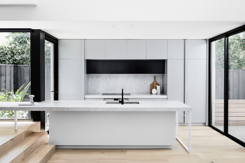 Inspiration for a mid-sized contemporary open plan kitchen in Melbourne with an undermount sink, grey cabinets, marble benchtops, white splashback, marble splashback, light hardwood floors, with island, white benchtop, flat-panel cabinets and beige floor.