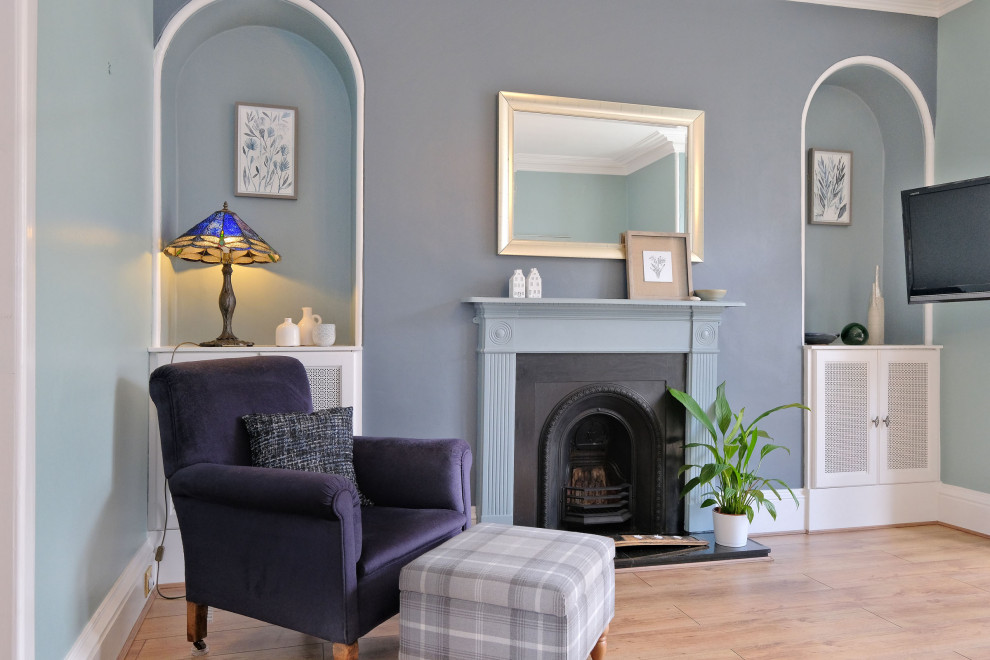 Design ideas for a medium sized classic living room in Other with blue walls, laminate floors, a standard fireplace, a wooden fireplace surround, a wall mounted tv, brown floors and a chimney breast.
