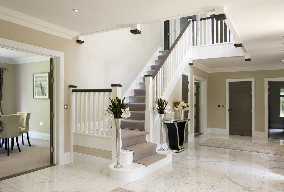 Design ideas for a mid-sized contemporary carpeted l-shaped staircase in Hampshire with carpet risers and wood railing.