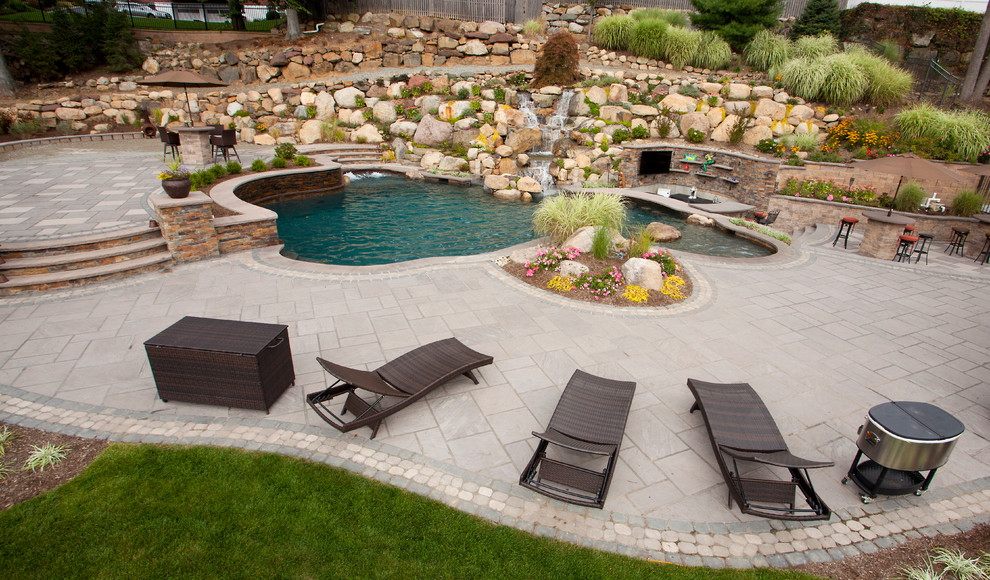 Photo of a large traditional backyard garden in New York with a water feature and concrete pavers.