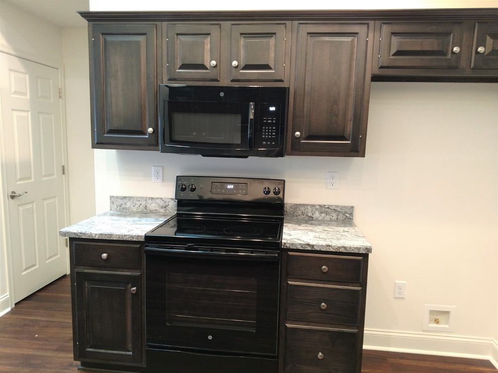 Mid-sized transitional u-shaped laminate floor and multicolored floor home design photo with a drop-in sink, raised-panel cabinets, dark wood cabinets, laminate countertops, multicolored backsplash, black appliances, a peninsula and multicolored countertops