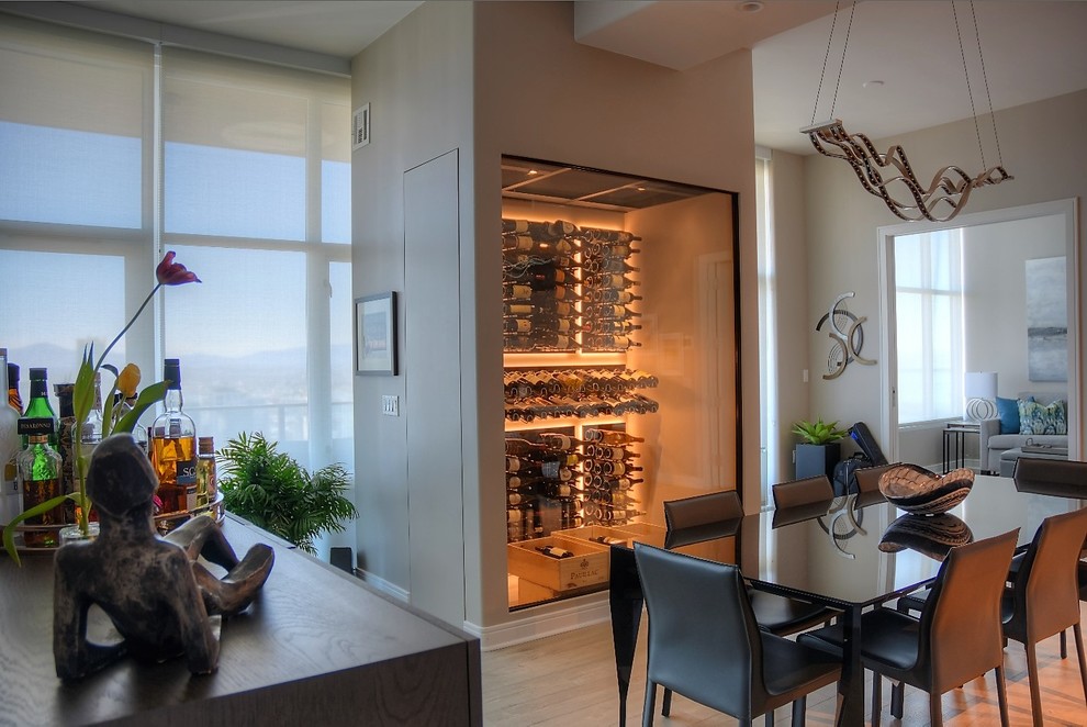 This is an example of a small modern wine cellar in San Diego with light hardwood floors and display racks.