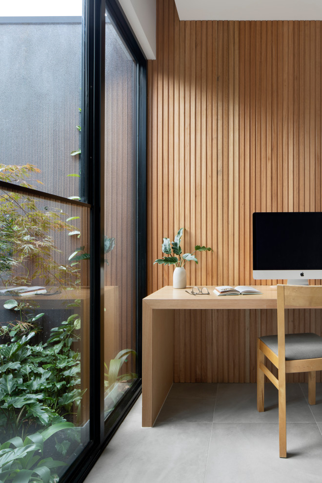 Ejemplo de despacho moderno de tamaño medio con suelo de baldosas de cerámica, escritorio empotrado, suelo gris y panelado