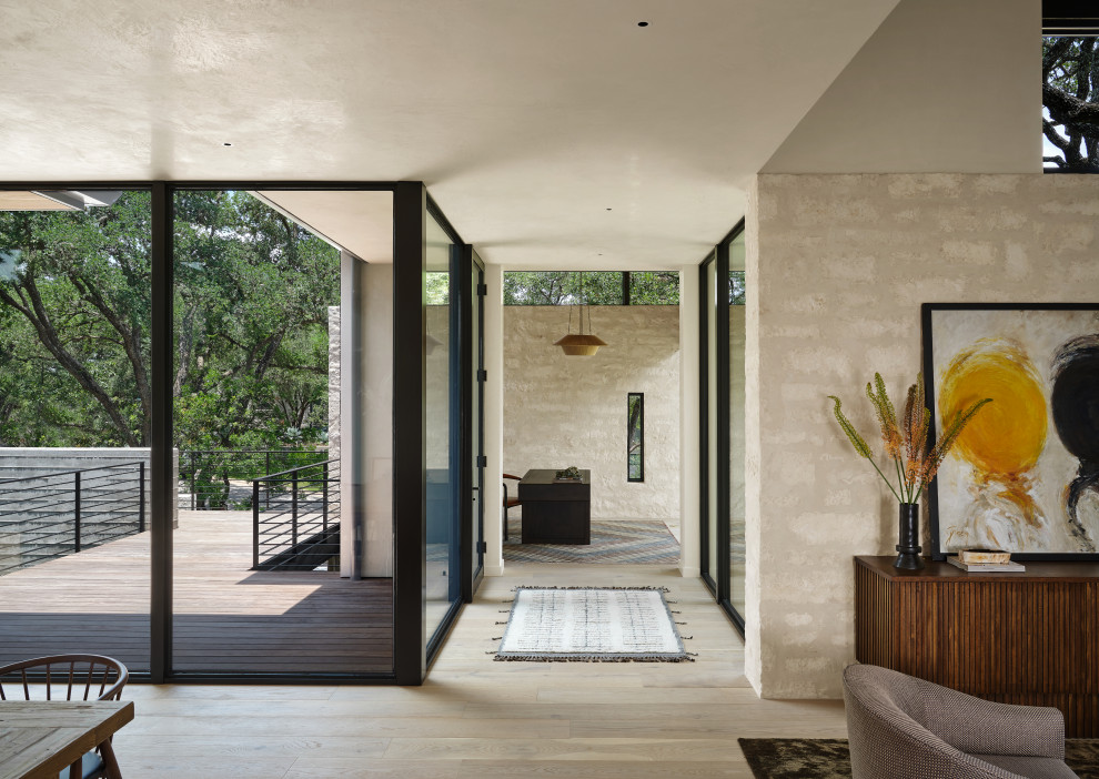 Mittelgroßer Moderner Eingang mit Korridor, weißer Wandfarbe, hellem Holzboden, Drehtür, Haustür aus Glas und beigem Boden in Austin