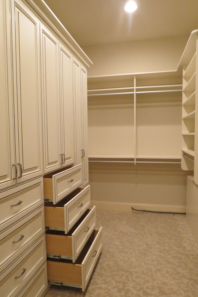 Photo of a large transitional gender-neutral walk-in wardrobe in Other with raised-panel cabinets, white cabinets and carpet.