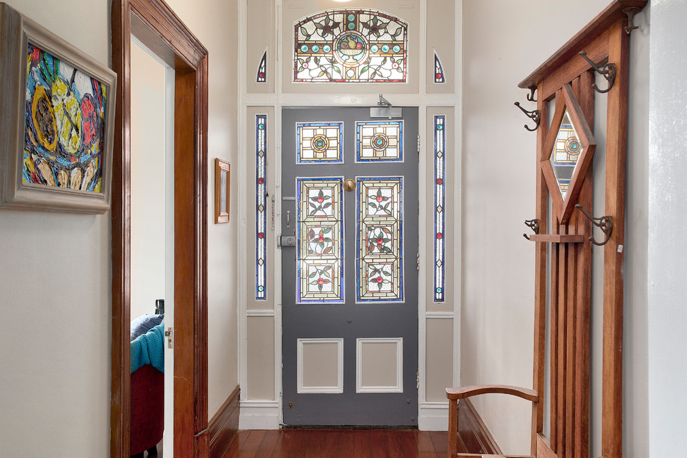 This is an example of a traditional front door in Sydney with beige walls, medium hardwood floors, a single front door, a gray front door and brown floor.