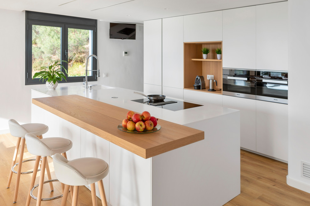 Design ideas for a beach style kitchen in Other with flat-panel cabinets, white cabinets, with island, white benchtop, a single-bowl sink and light hardwood floors.