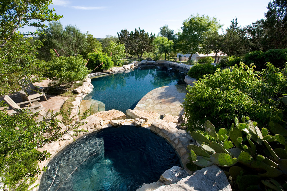 Mid-sized country backyard custom-shaped natural pool in Austin with a hot tub and natural stone pavers.