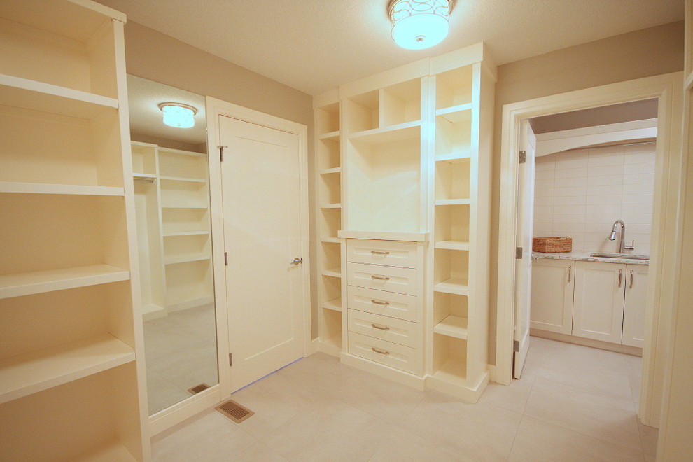 Transitional gender-neutral walk-in wardrobe in Calgary with shaker cabinets, white cabinets and ceramic floors.