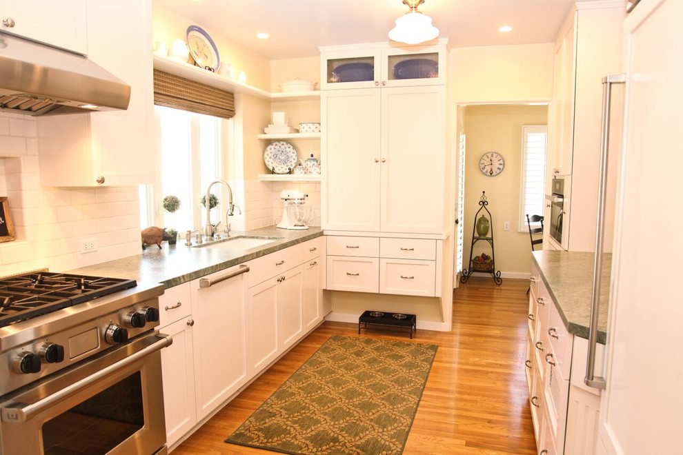 Inspiration for a mid-sized traditional galley separate kitchen in San Diego with an undermount sink, shaker cabinets, white cabinets, quartz benchtops, white splashback, subway tile splashback, panelled appliances, medium hardwood floors, no island and brown floor.