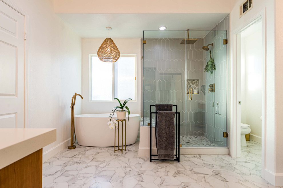 This is an example of a large transitional master bathroom in Orange County with flat-panel cabinets, medium wood cabinets, a freestanding tub, a corner shower, a one-piece toilet, gray tile, porcelain tile, white walls, marble floors, an undermount sink, engineered quartz benchtops, multi-coloured floor, a hinged shower door, white benchtops, a shower seat, a single vanity, a built-in vanity, wallpaper and wallpaper.