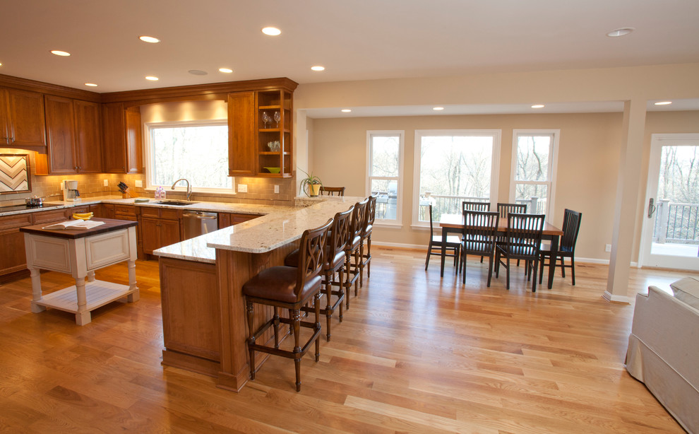 Inspiration for a large transitional u-shaped light wood floor and beige floor open concept kitchen remodel in Cincinnati with an undermount sink, recessed-panel cabinets, medium tone wood cabinets, granite countertops, brown backsplash, stainless steel appliances, an island and beige countertops