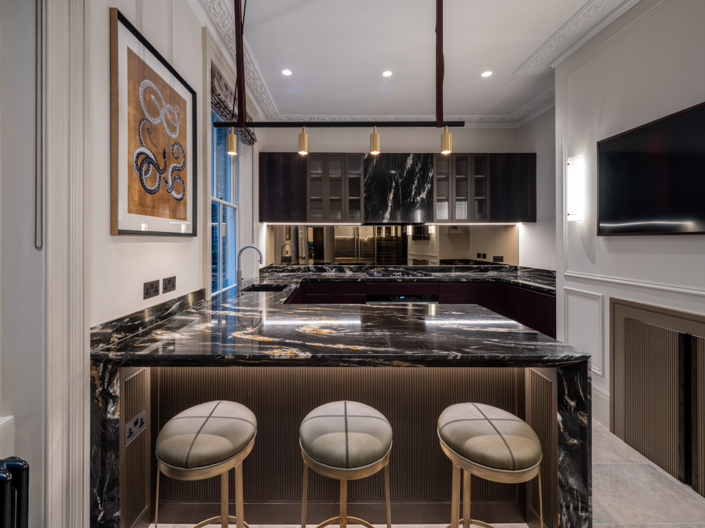Design ideas for a mid-sized traditional u-shaped kitchen in London with an undermount sink, flat-panel cabinets, dark wood cabinets, marble benchtops, metallic splashback, mirror splashback, stainless steel appliances, marble floors, with island, beige floor and black benchtop.