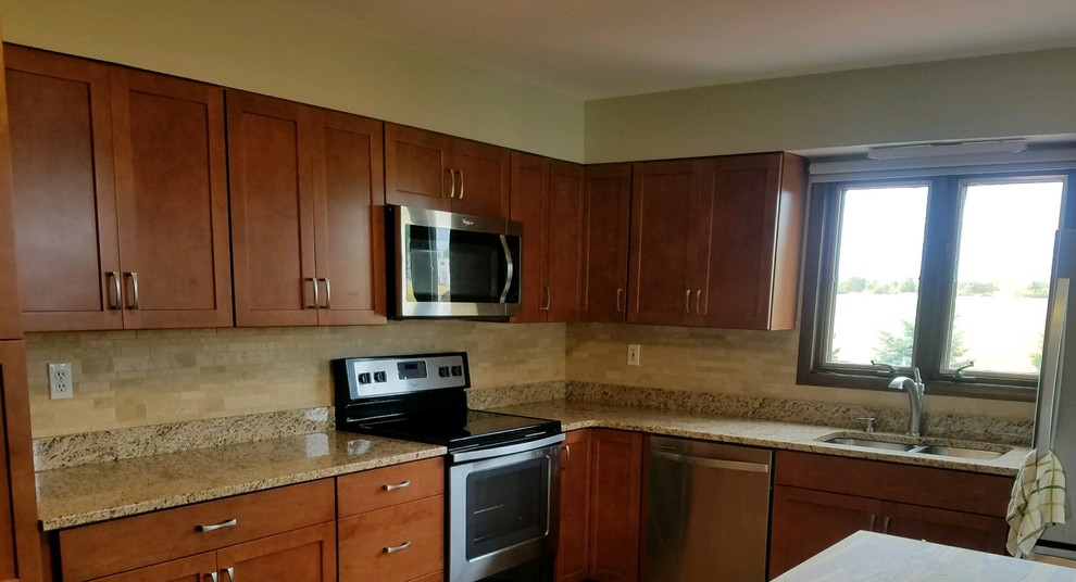Mid-sized transitional l-shaped kitchen photo with a double-bowl sink, recessed-panel cabinets, granite countertops, beige backsplash, mosaic tile backsplash and stainless steel appliances