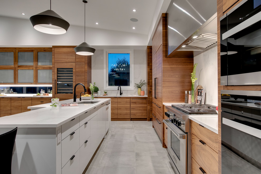 Photo of a large modern l-shaped eat-in kitchen in Calgary with an undermount sink, flat-panel cabinets, medium wood cabinets, quartz benchtops, white splashback, marble splashback, panelled appliances, ceramic floors, with island, grey floor and white benchtop.