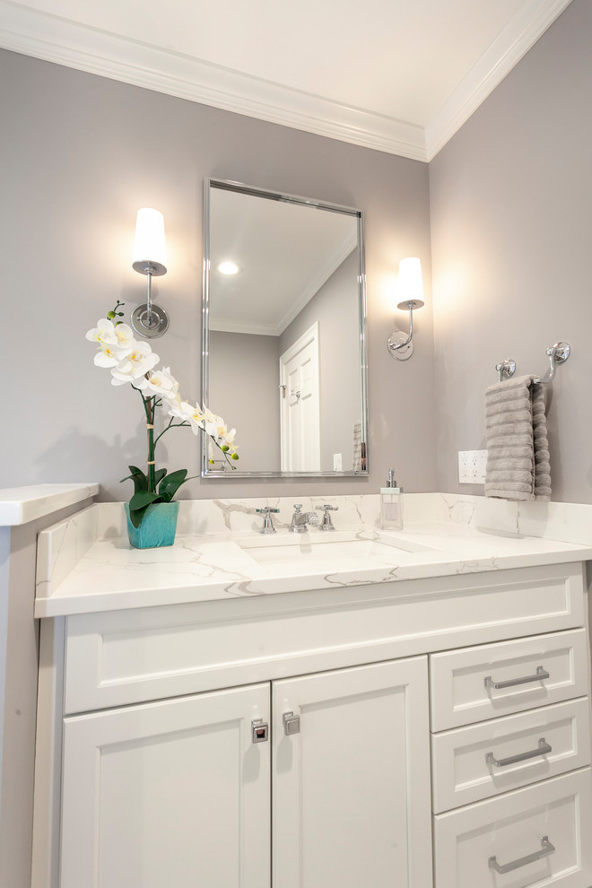 Mid-sized transitional master bathroom in Bridgeport with recessed-panel cabinets, white cabinets, an alcove shower, a two-piece toilet, white tile, ceramic tile, grey walls, porcelain floors, an undermount sink, engineered quartz benchtops, grey floor, a hinged shower door and white benchtops.