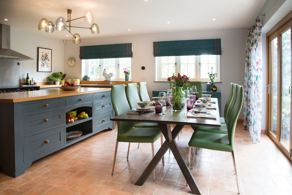 This is an example of a mid-sized transitional eat-in kitchen in Kent with terra-cotta floors and orange floor.