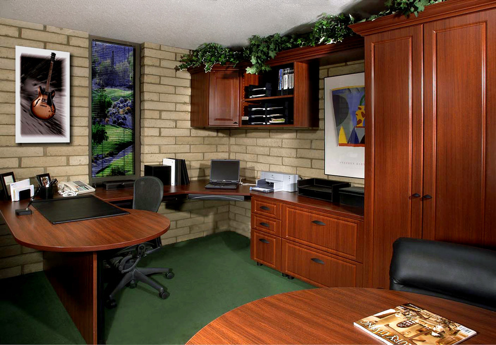 This is an example of a mid-sized traditional study room with beige walls, carpet, a built-in desk and green floor.