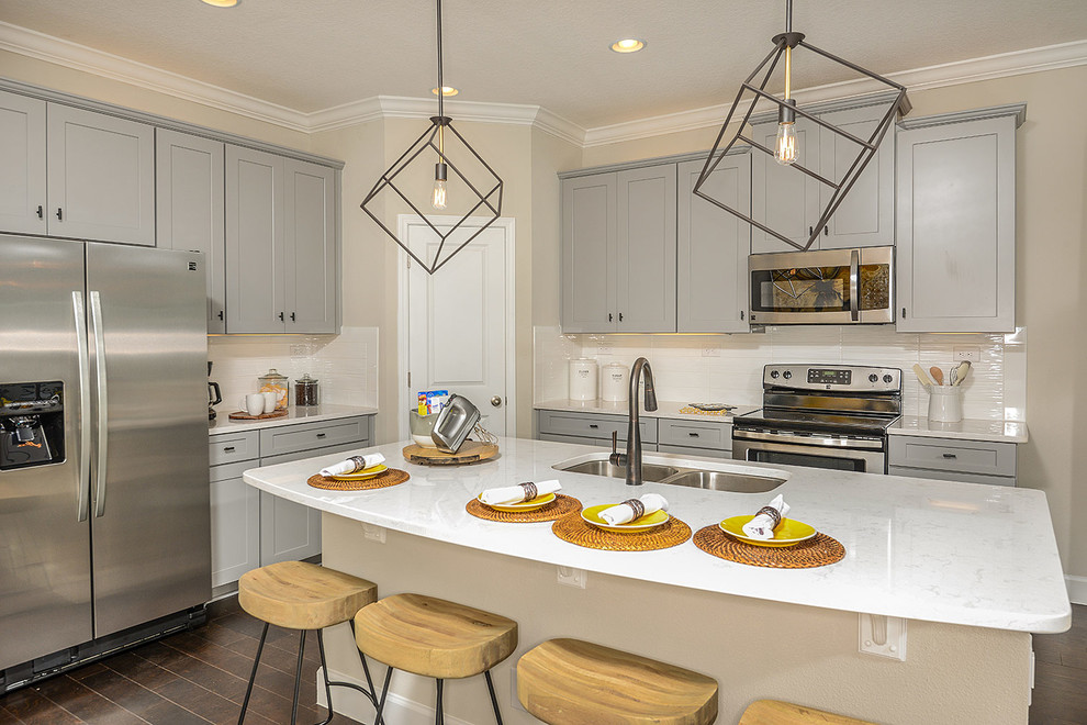 Design ideas for a transitional kitchen in Orlando with a double-bowl sink, shaker cabinets, grey cabinets, white splashback, stainless steel appliances and with island.