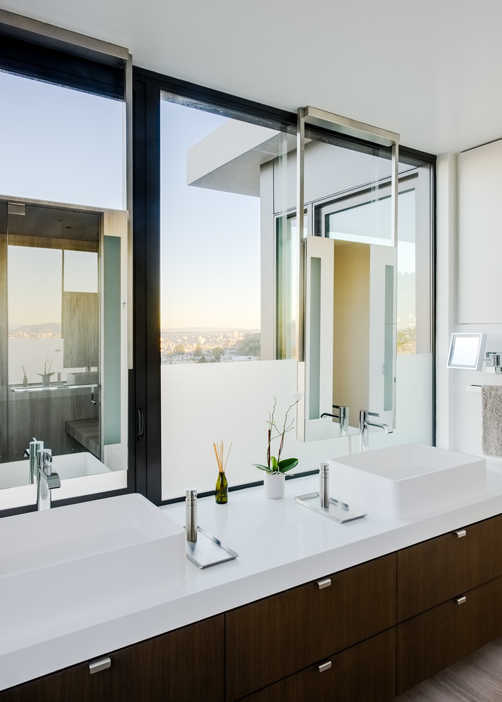 Modern bathroom in San Francisco with flat-panel cabinets, dark wood cabinets, white walls, a vessel sink, beige floor and white benchtops.