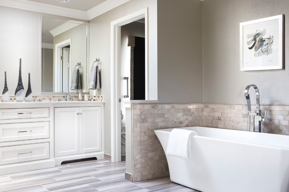 Inspiration for a mid-sized transitional master bathroom in Kansas City with recessed-panel cabinets, white cabinets, a freestanding tub, an alcove shower, a two-piece toilet, gray tile, porcelain tile, grey walls, porcelain floors, an undermount sink and engineered quartz benchtops.