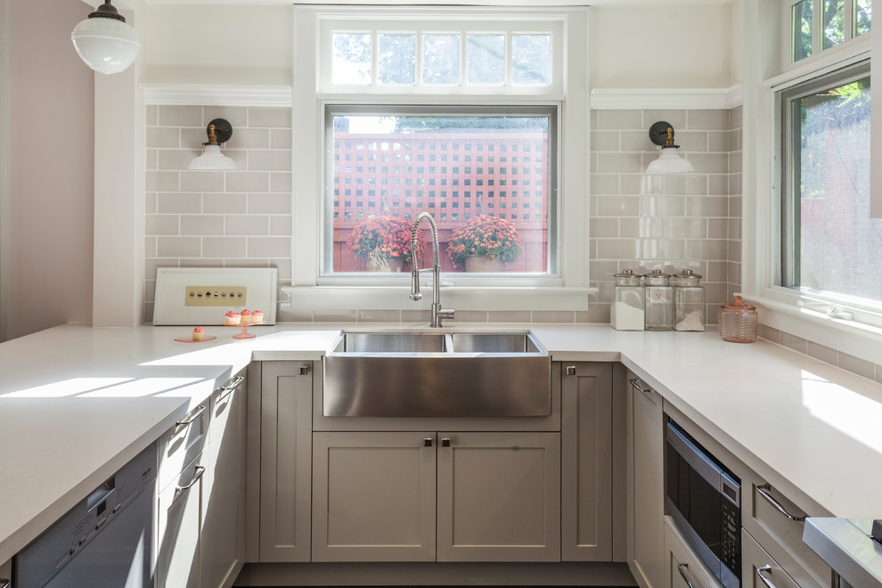 Inspiration for a mid-sized eclectic u-shaped dark wood floor open concept kitchen remodel with a farmhouse sink, shaker cabinets, gray cabinets, quartz countertops, gray backsplash, subway tile backsplash, stainless steel appliances and a peninsula