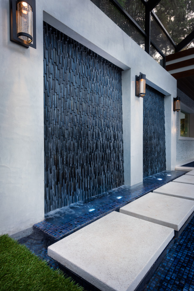 Esempio di una grande piscina a sfioro infinito design personalizzata dietro casa con piastrelle