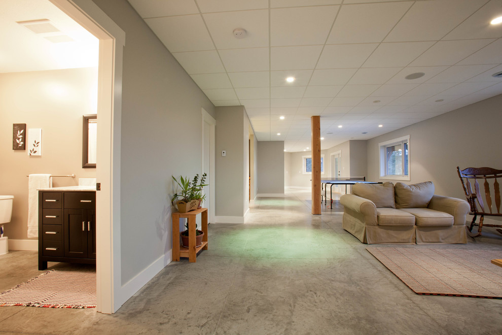This is an example of a large traditional walk-out basement in Vancouver with grey walls, concrete floors and no fireplace.